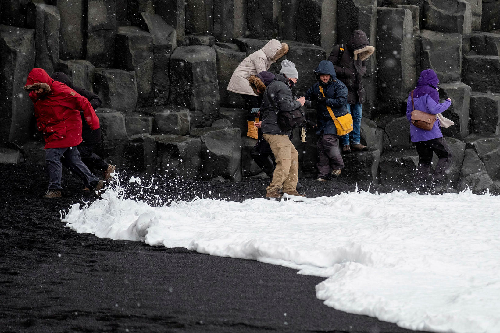 Tourists trying to get away from the waves on Reynisfjara …