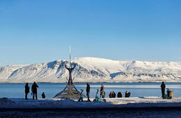 Tourists by the sculpture The Sun Voyager by Jón Gunnar Árnason by Sæbraut in Reykjavík facing Mt Esja and the open sea.