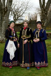 The photo shows three women wearing recreated costumes by Guðrún Skúladóttir: Erla Rúrí in the center wearing the recreated bridal costume, alongside Guðlaug and Hildur in 18th-century faldbúningur costumes with recreated skirts by Guðrún Skúladóttir.