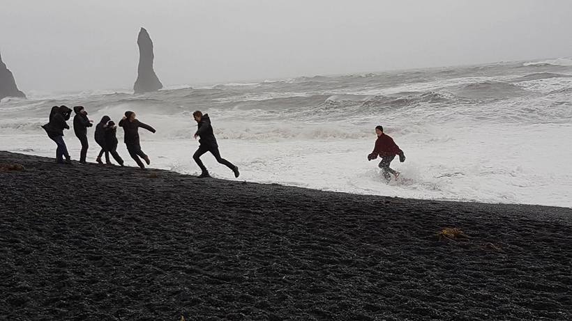 Tourists running into the waves and laughing at Iceland's most …