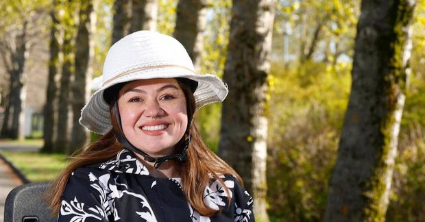 Eva er á rauðu rafmagnshjóli með körfu undir töskuna sína.