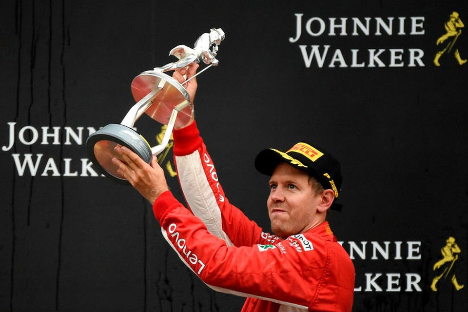 Sebastian Vettel hampar verðlaunagrip sínum í Spa; styttu af viskíkónginum Jóni á röltinu.
