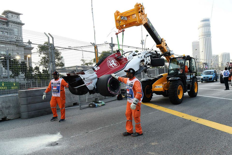 Brautarverðir fjarlægja bíl Charles Leclerc sem skall á öryggisvegg undir lok æfingarinnar í Singapúr í …