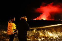 Viðbragðsaðli ásamt ferðamanni við Grindavíkurveg virða fyrir sér gosið nú á áttunda tímanum.