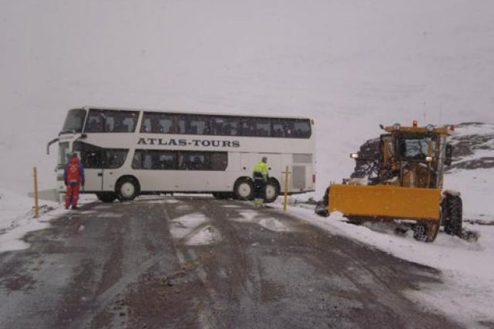 Önnur rútan snerist þversum á veginum. Veghefill dró hana upp …