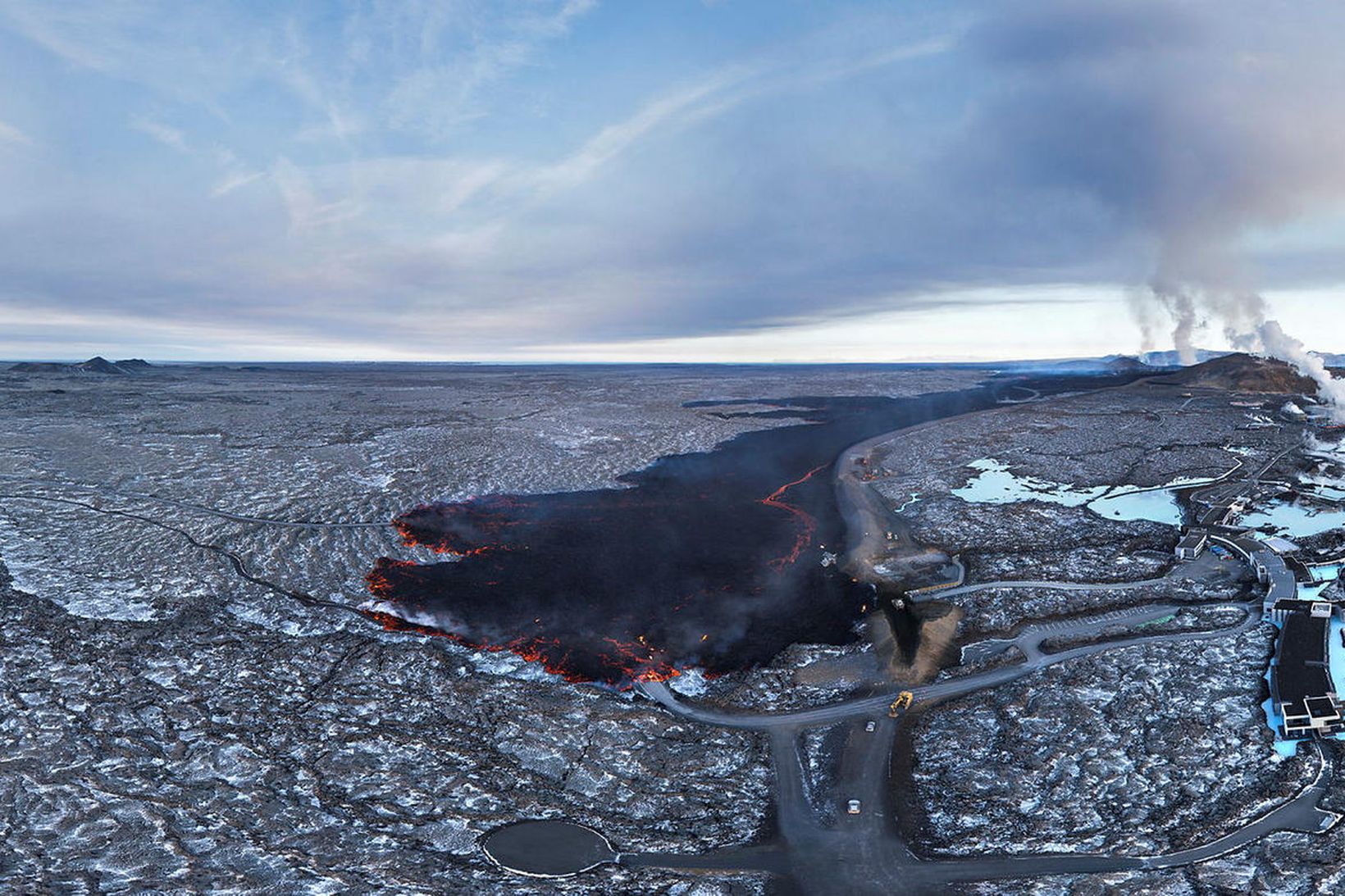 Séð yfir Bláa lónið, nýja hraunið, varnargarðinn og náttúrulegan þröskuld …