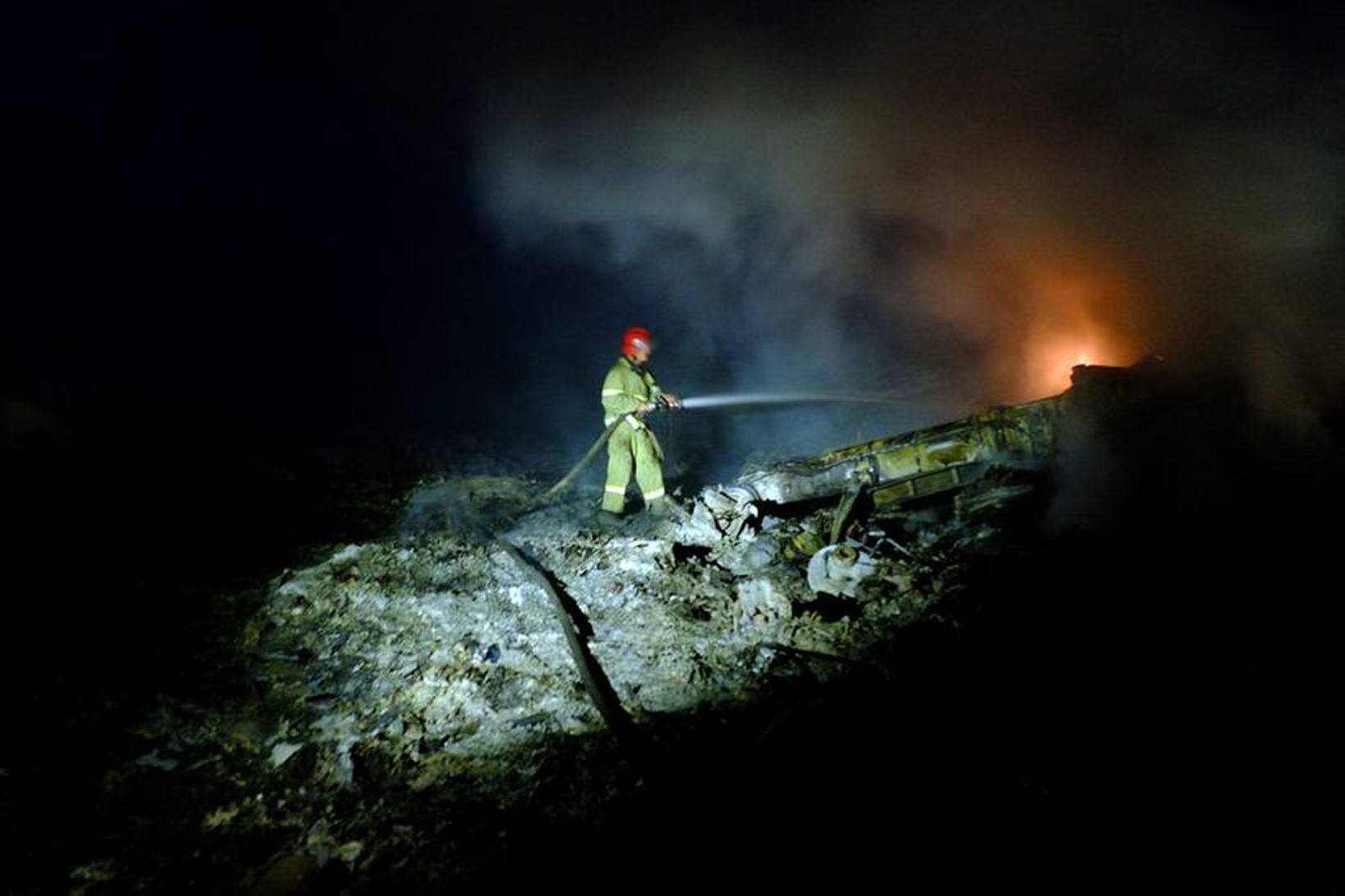 Slökkviliðsmaður að störfum við flakið.