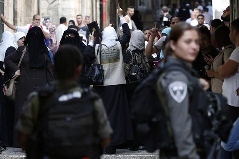 Palestinians shout slogans in front of Israeli security forces who block a street leading to the Al-Aqsa mosque compound, in the Muslim quarter in Jerusalem's Old City yesterday.