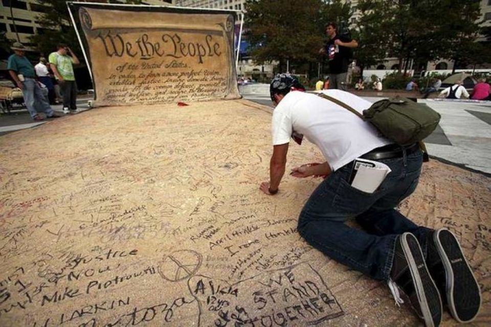 A man signs a huge copy of U.S. Constitution at the Occupy D.C camp in …