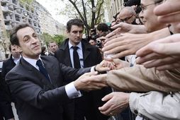 Fylgjendur forsetans Nicolas Sarkozy fagna honum er hann mætti á kjörstað í morgun.