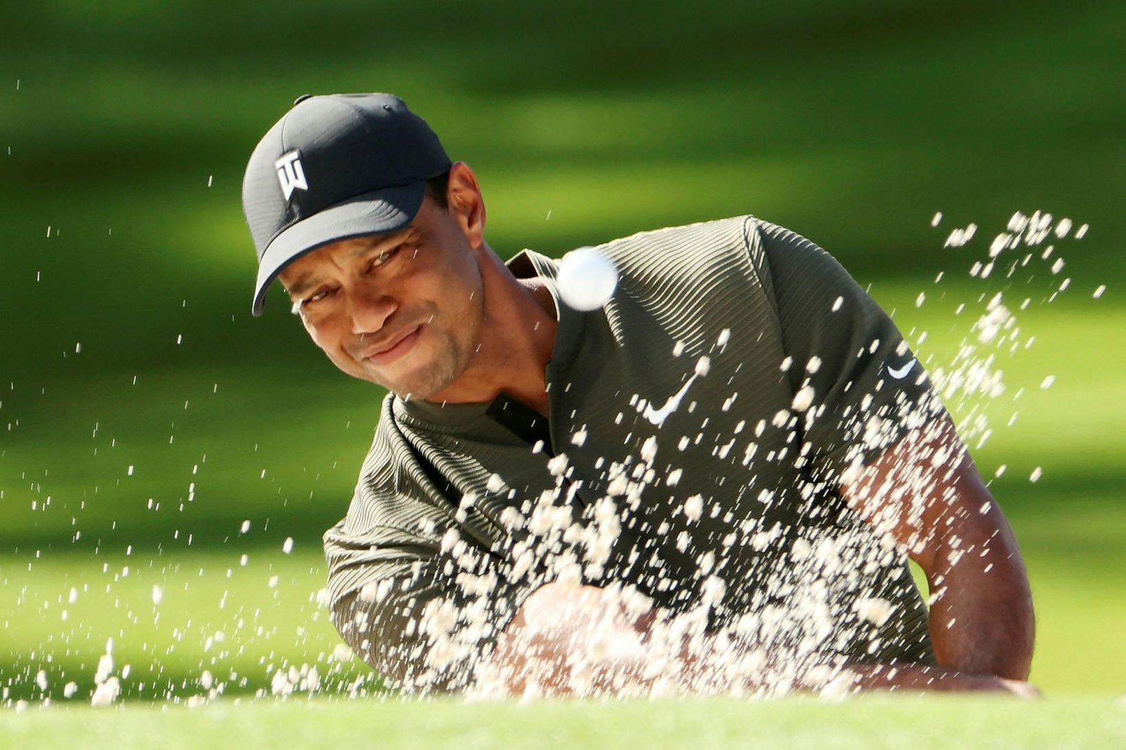 Tiger Woods slær upp úr sandgryfju á hringnum í dag.