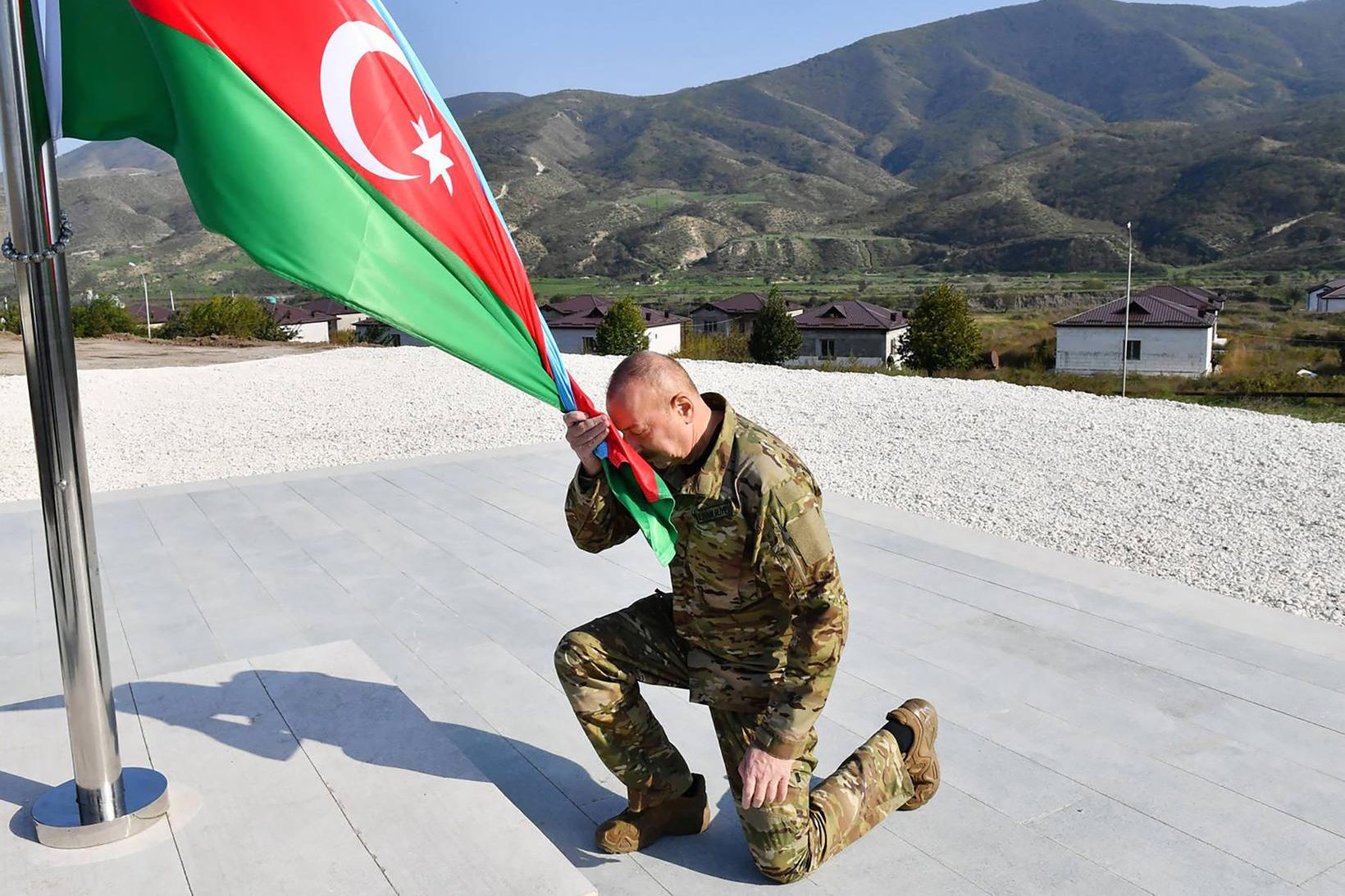 Ilham Aliyev, forseti Aserbaídsjan, krýpur fyrir framan þjóðarfánann. Aserbaídsjanar hafa …