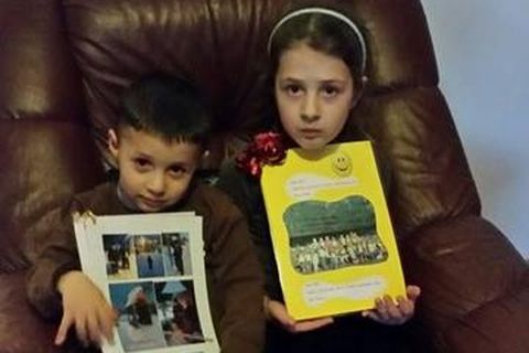 Kevi, aged three, and his sister Klea clutching their memento books from playschool before being deported.
