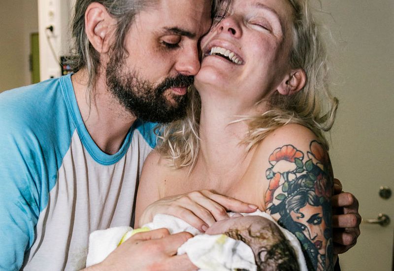 Andrea and her boyfriend holding their newborn son.