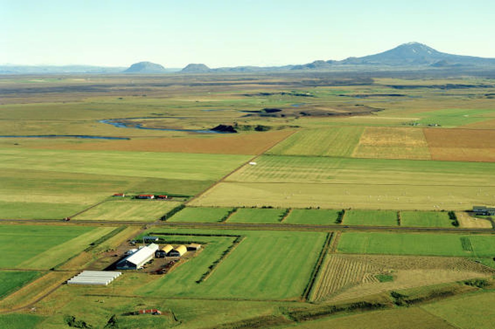 Verksmiðjuhúsin á Stórólfsvelli til vinstri á myndinni. Hekla er í …