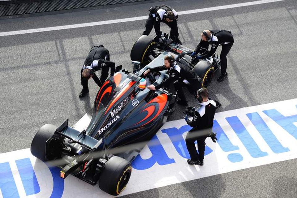 Vélvirkjar McLaren ýta bíl Fernando Alonso inn í bílskúr milli aksturslota í Barcelona í dag.