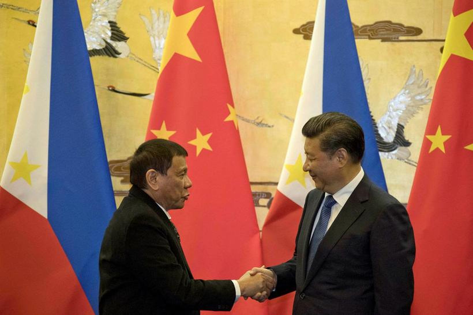Rodrigo Duterte og Xi Jinping takast í hendur.