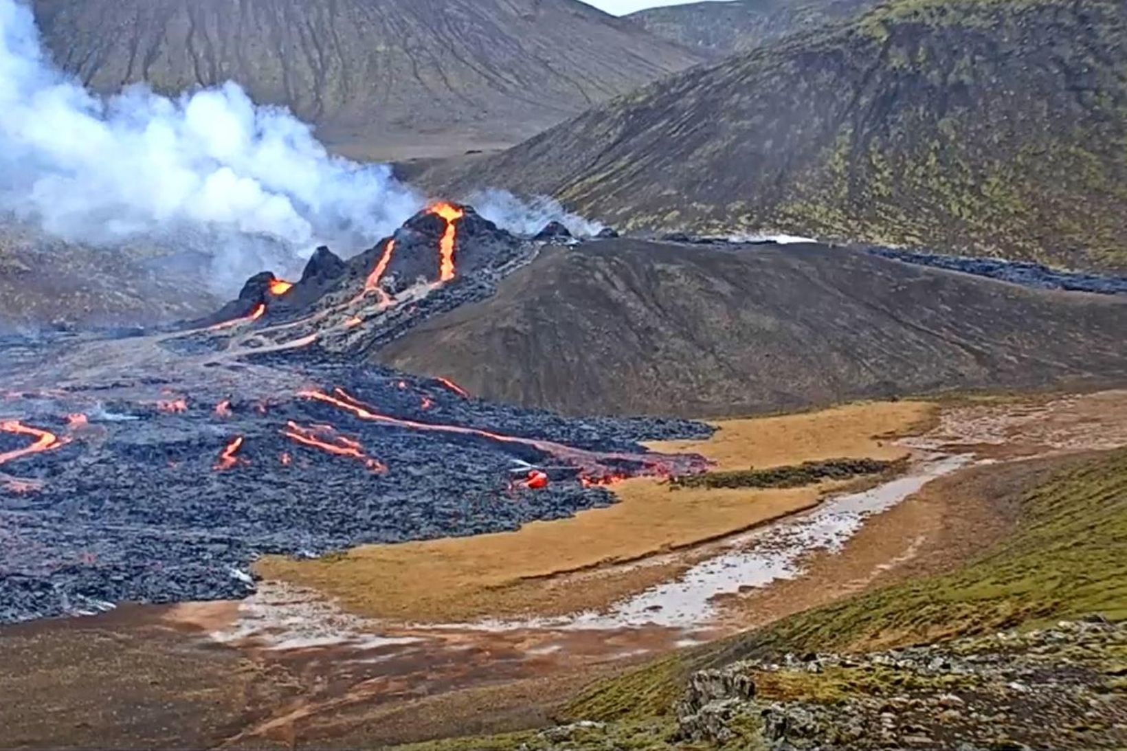 Á þessu skjáskoti má sjá tvær þyrlur við eldstöðvarnar um …