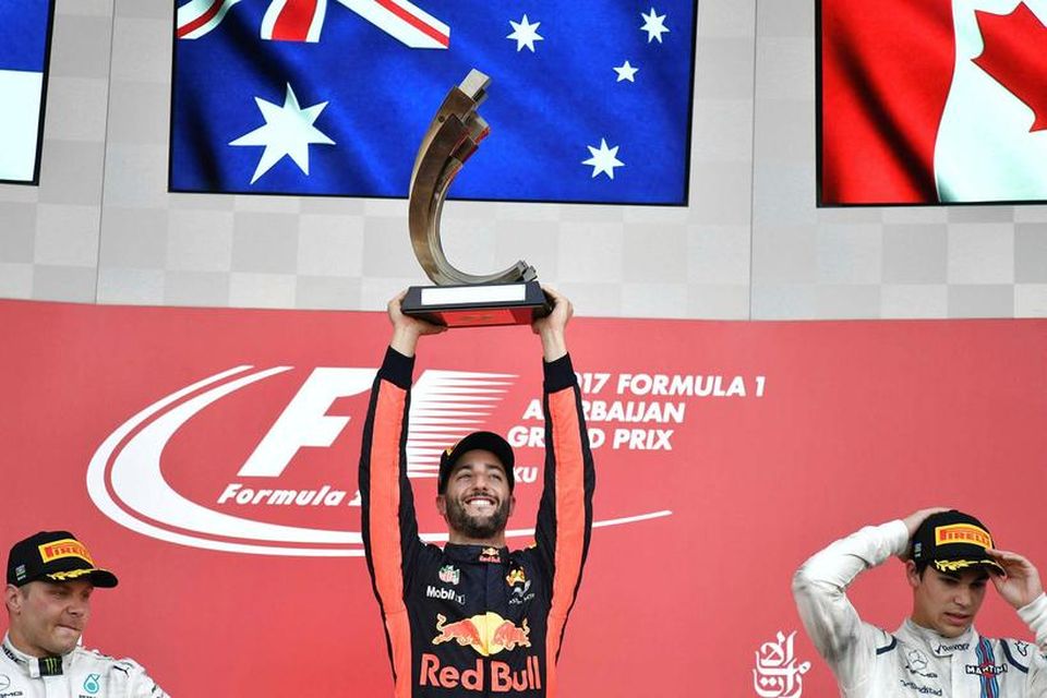 Daniel Ricciardo hefur verðlaunagrip sinn á loft á pallinum í Bakú. Til vinstri er Valtteri …