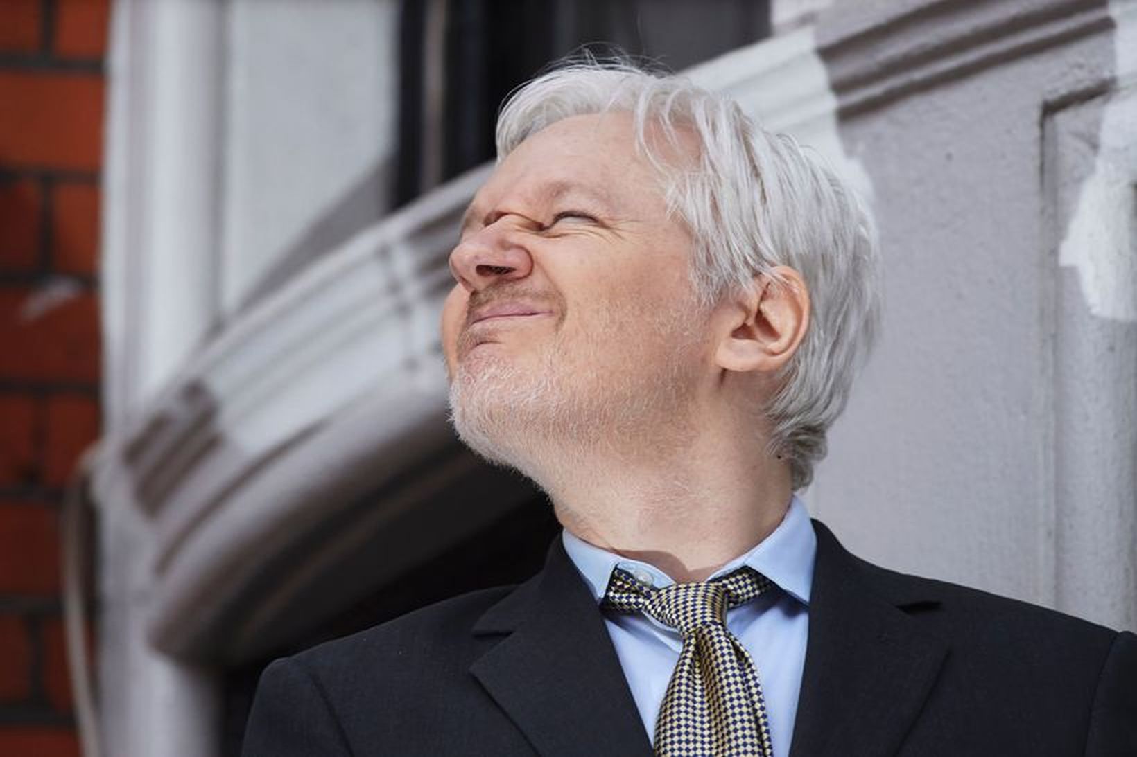Assange með pírð augun gegnt sólu.