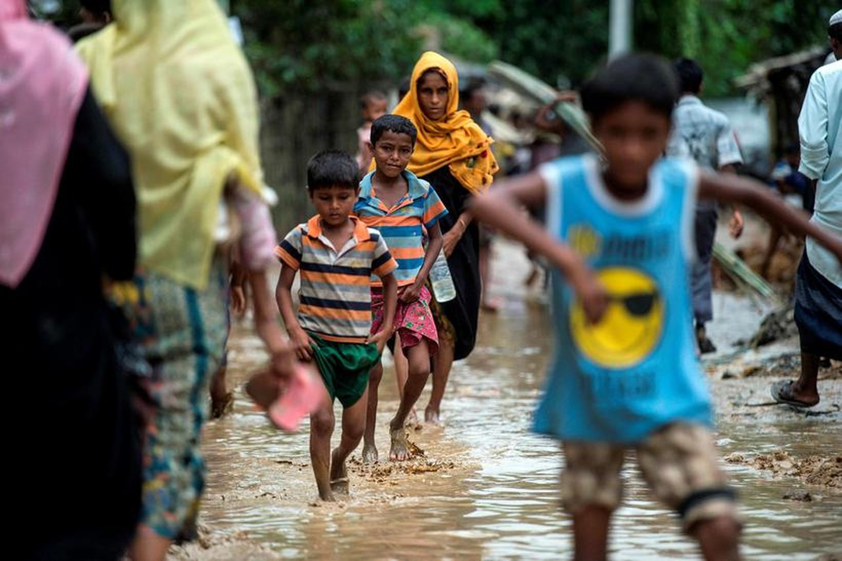 Rohingjar vaða flóðavatn í flóttamannabúðum í Bangladess.