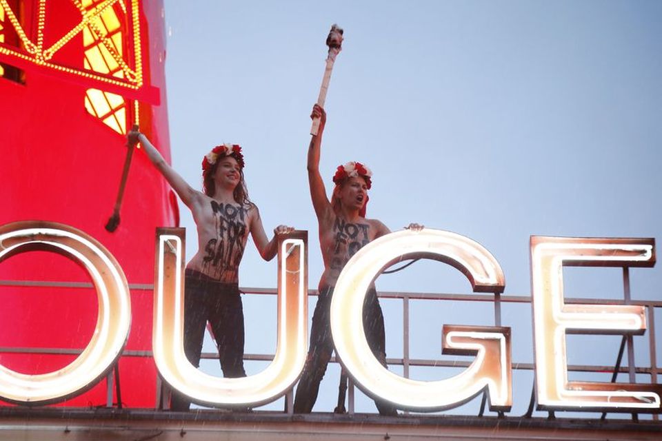 Tveir meðlimir Femen mómæla berbrjósta á þaki Rauðu myllunnar í París - eða Moulin Rouge …