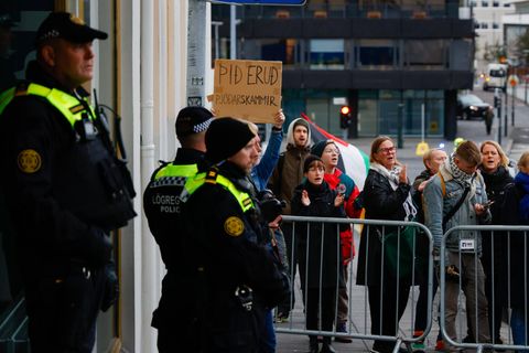 Lögreglan stendur vörð fyrir utan ríkisstjórnarfund, þar sem saman er kominn nokkur fjöldi fólks til …