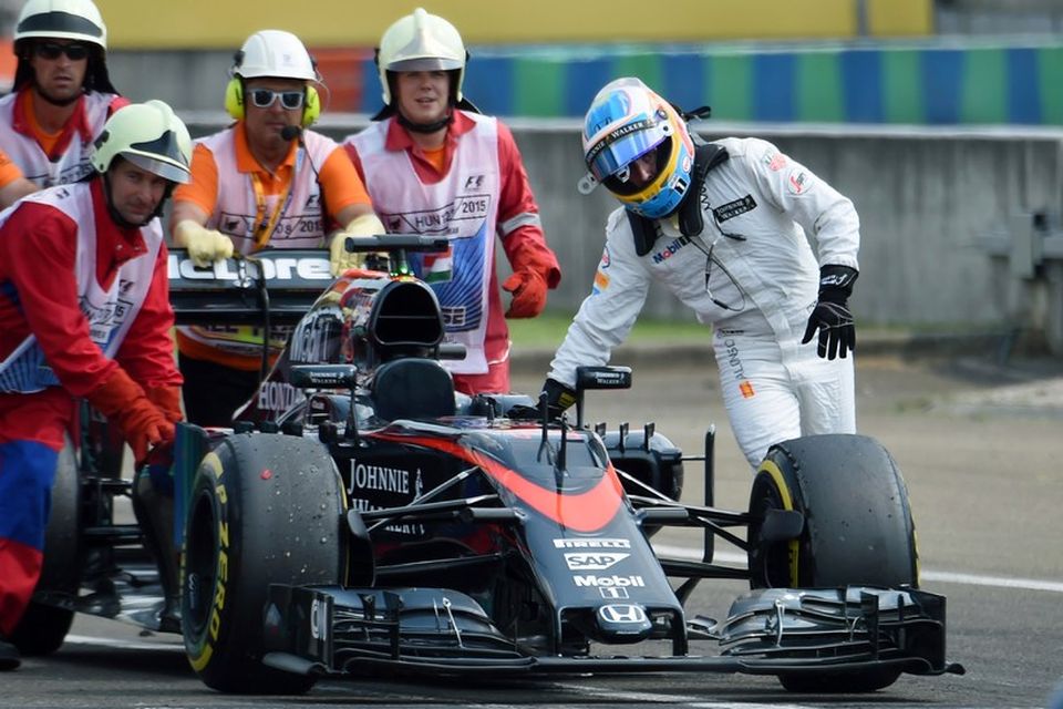 Fernando Alonso og brautarverðir komnir með McLarenbílinn að bílskúr liðsins í Búdapest.