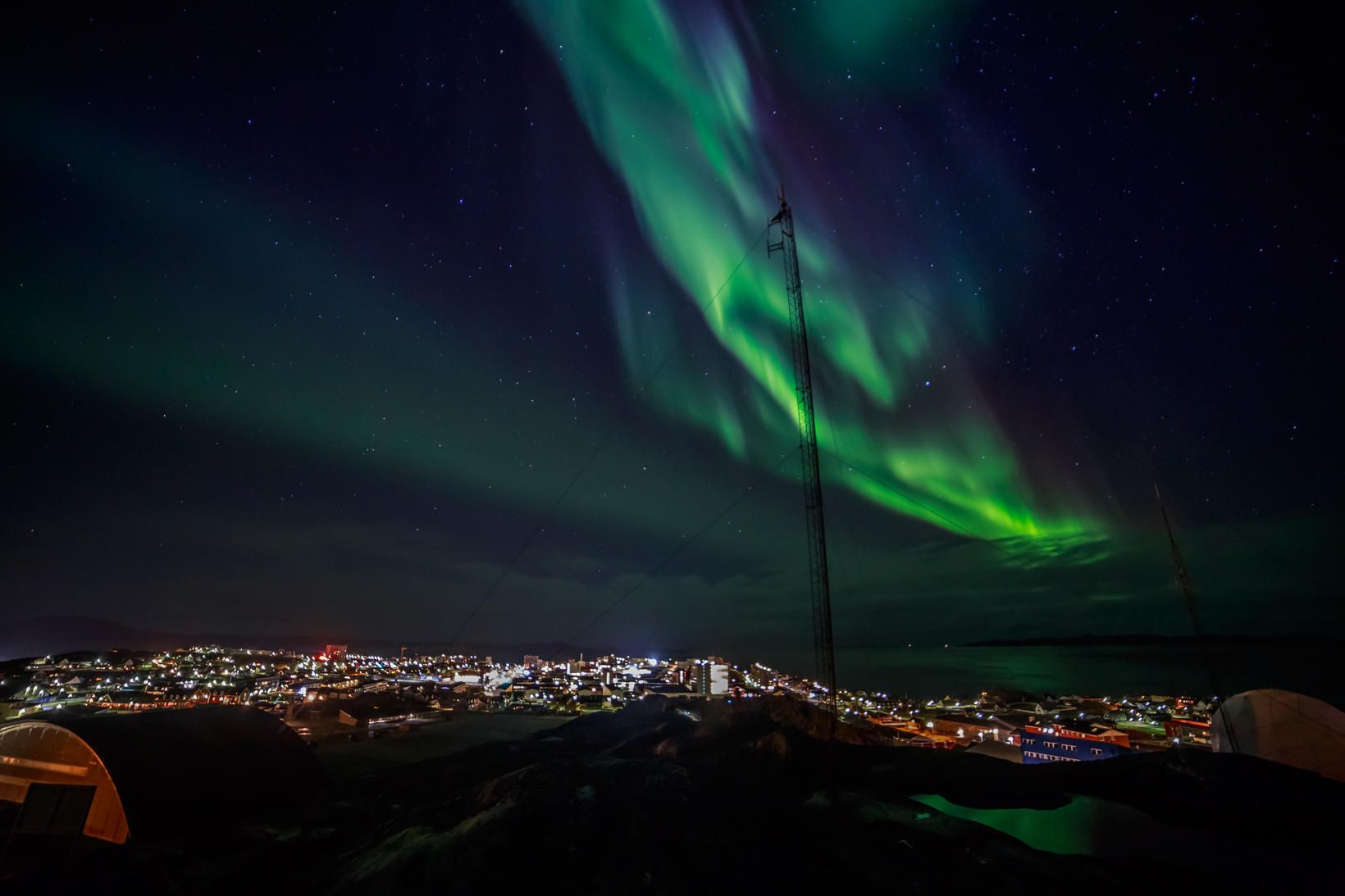 Beðið eftir grænu ljósi. Norðurljós sjást hér dansa yfir Nuuk, …