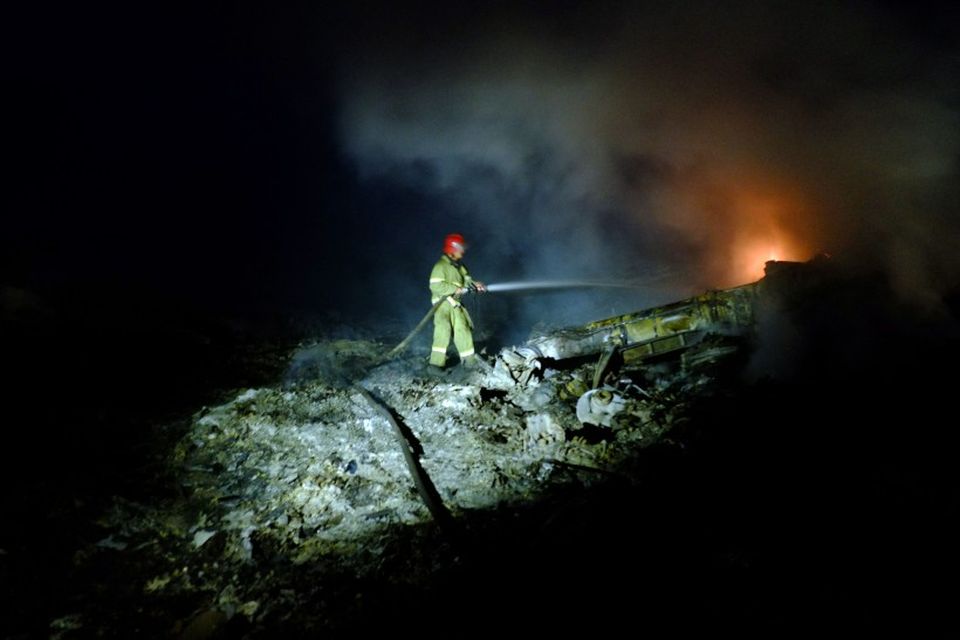 Slökkviliðsmaður vinnur við að slökkva eld í flaki vélarinnar.