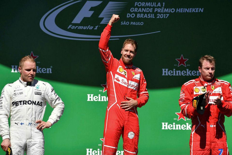 Sebastian Vettel fagnar á efsta þrepi verðlaunapallsins í Sao Paulo með Finnana Valtteri Bottas (t.v.) …
