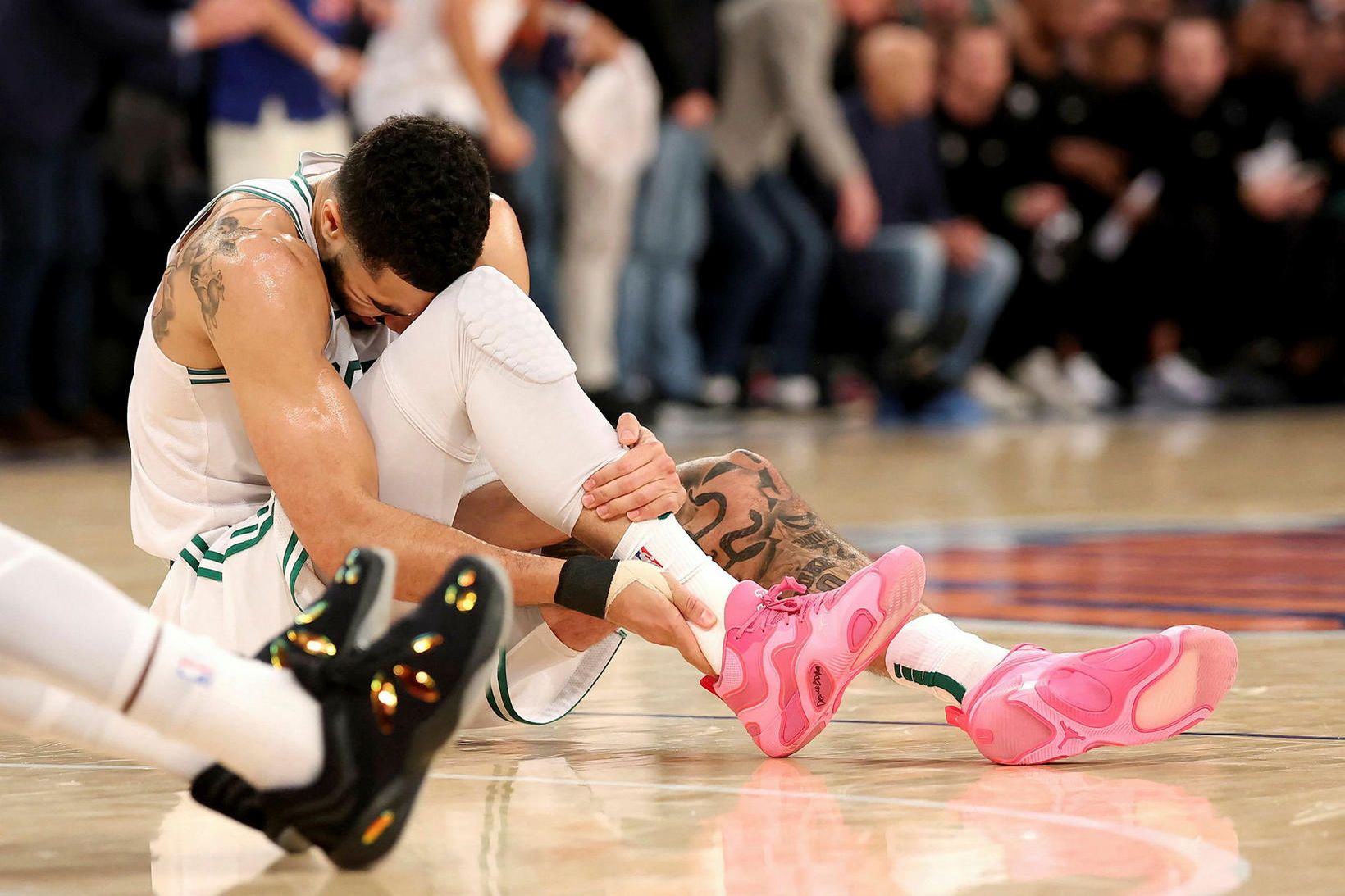 Jayson Tatum heldur um hásinina á hægri fæti eftir að …