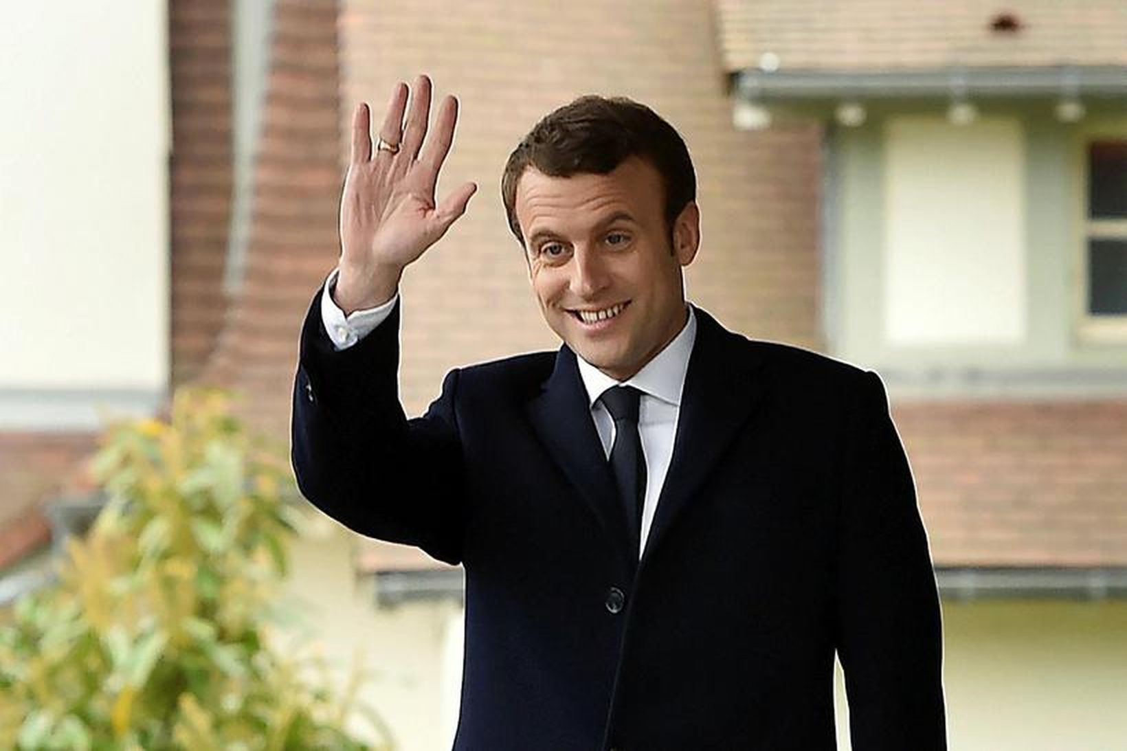 Emmanuel Macron veifar stuðningsmönnum sínum eftir að hafa greitt atkvæði.