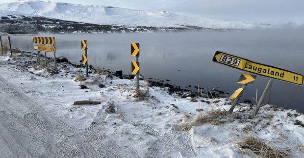 Bifreiðin hafnaði á skiltinu og endaði úti í sjó.