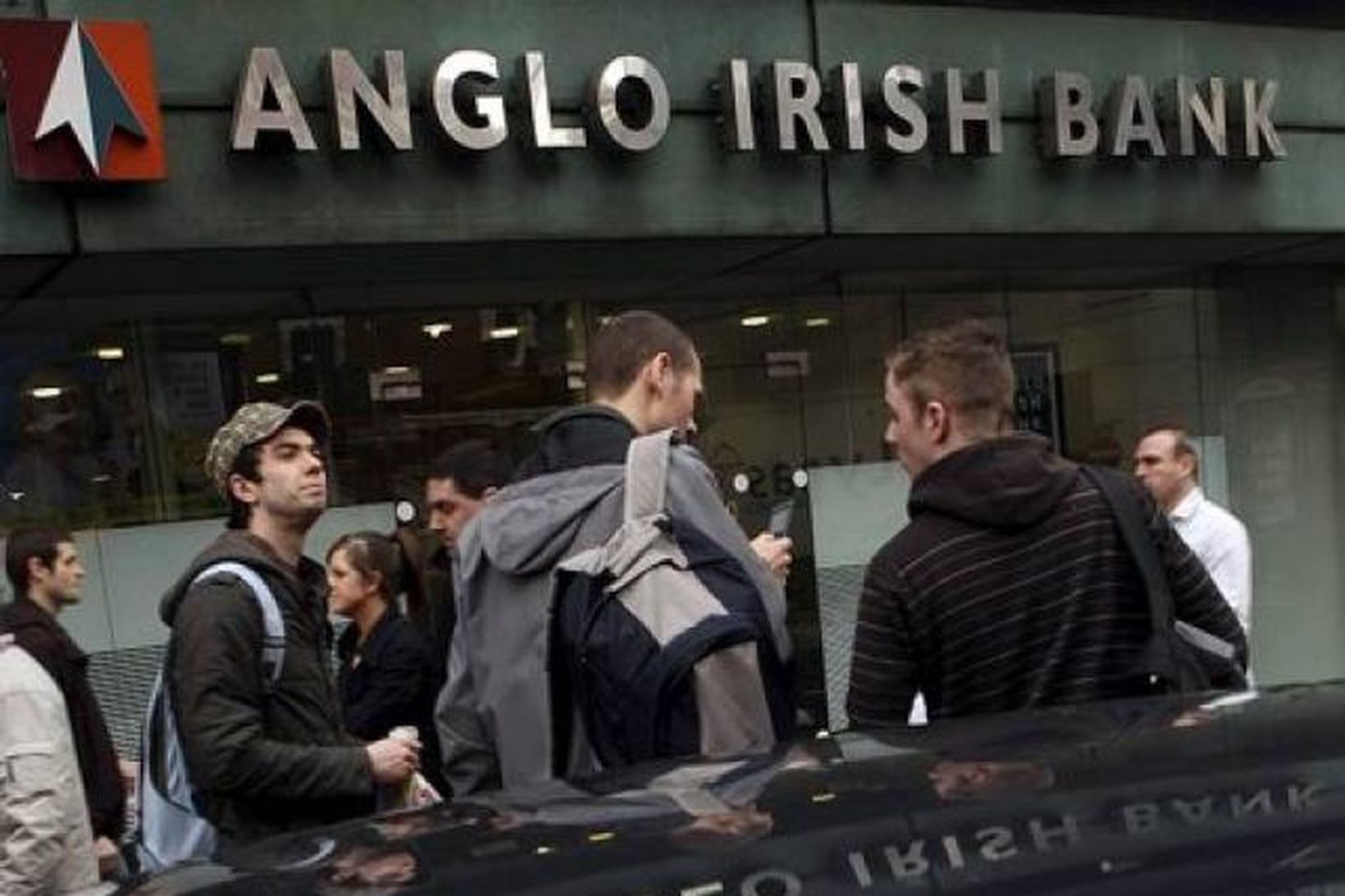 Vegfarendur ganga fram hjá höfuðstöðvum Anglo Irish Bank í Belfast.