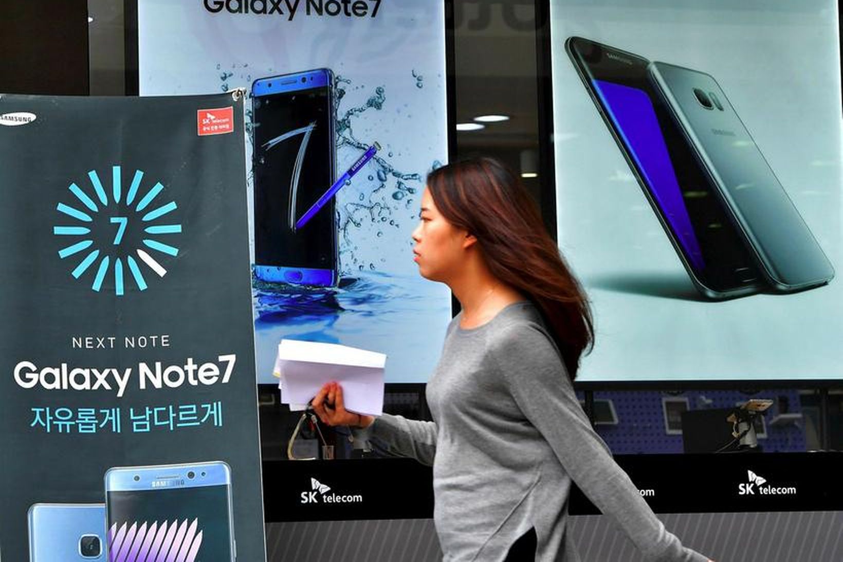 Kona gengur framhjá auglýsingaskiltum fyrir Samsung Galaxy Note 7.