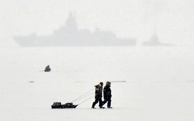 Veiðimenn ganga yfir ísilagðan Kirjálabotn við Sankti Pétursborg. Í bakgrunni hvílir herskip. Mynd frá desember …