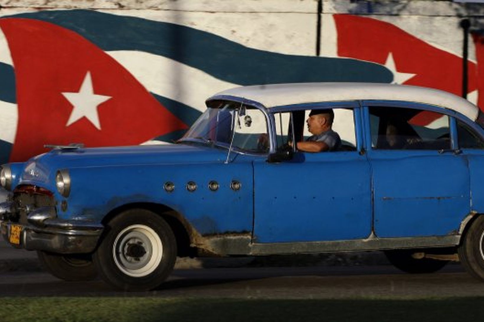 Frá Havana höfuðborg Kúbu. Buick 1955 keyrir hjá vegg sem …