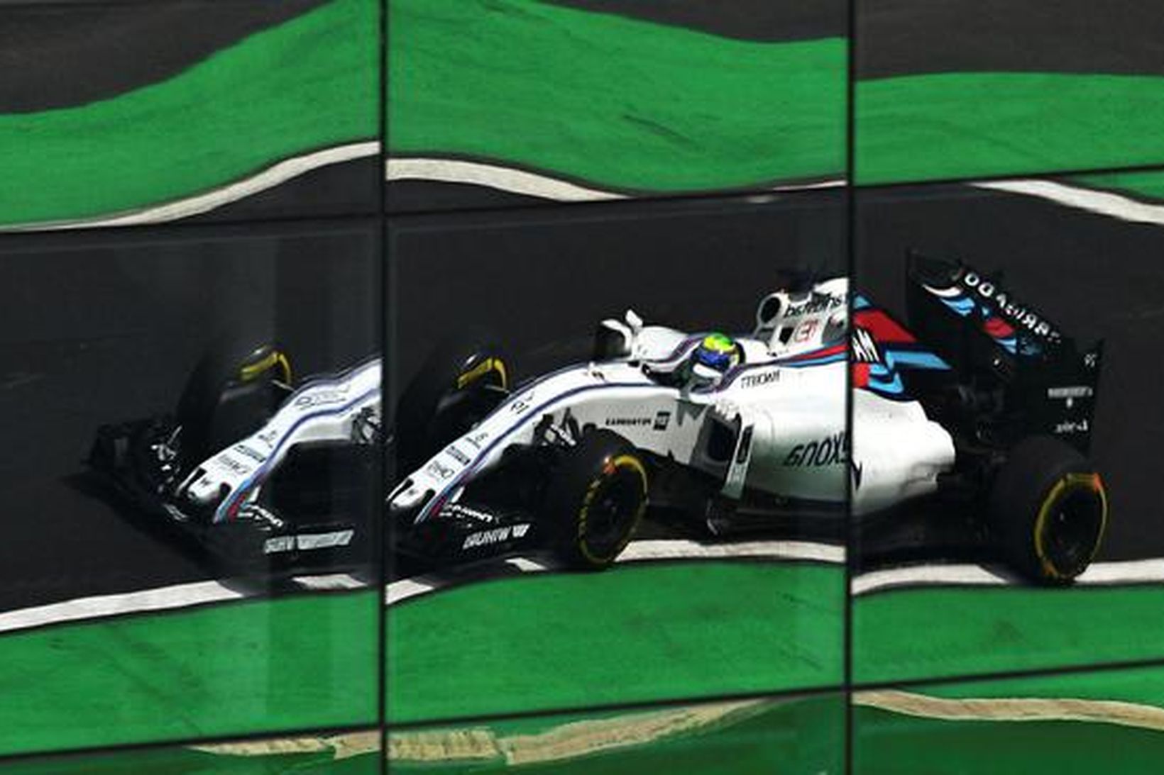 Bíll Felipe Massa speglast í glervegg aðalstúkunnar í Sao Paulo.