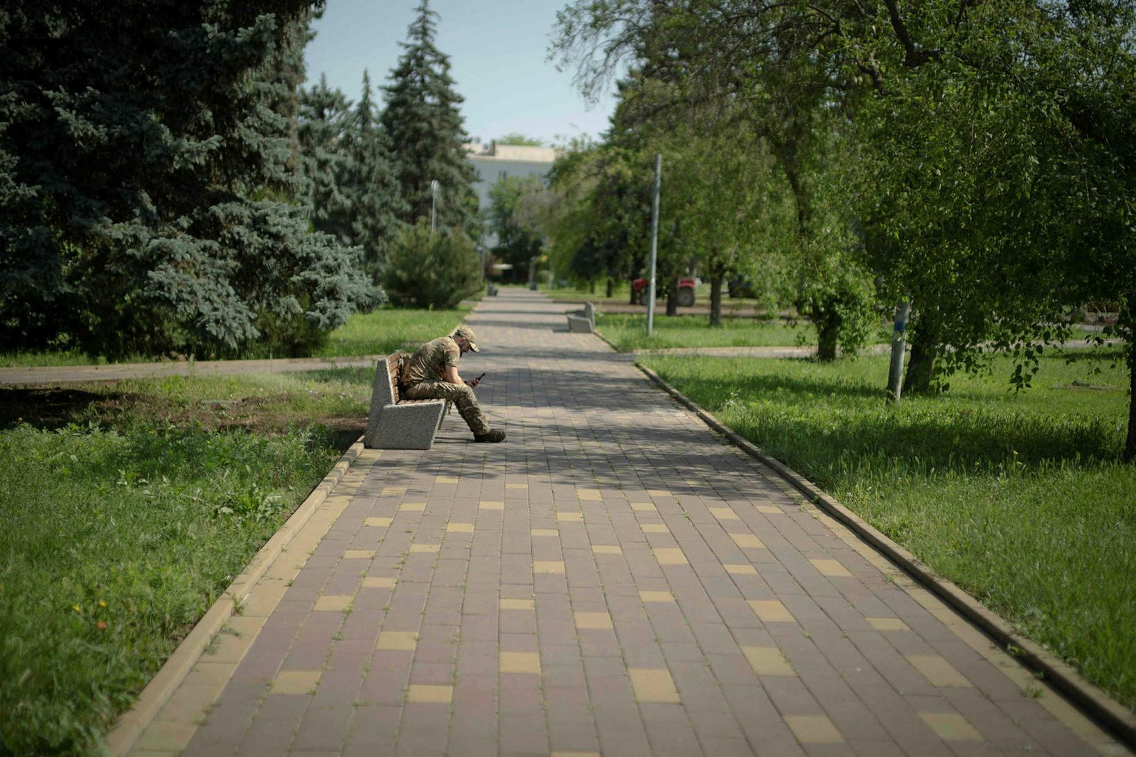 Úkraínskur hermaður hvílir lúin bein á bekk í Kramatorsk-garðinum í …