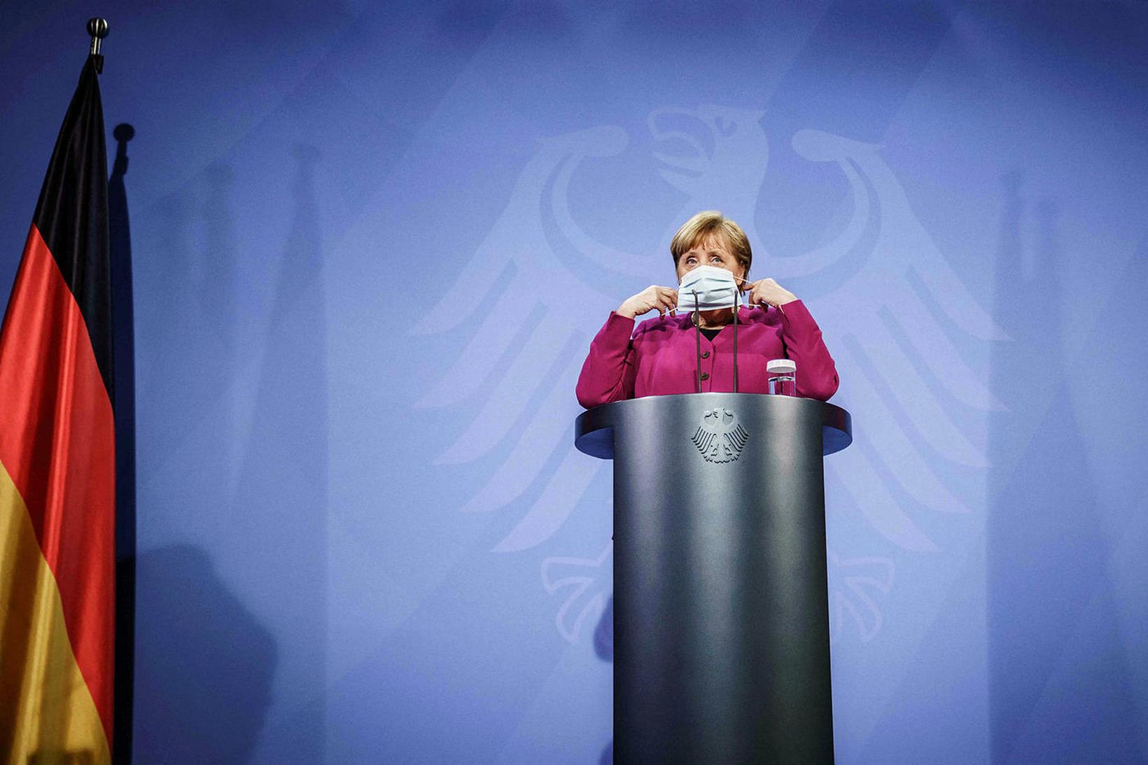 Angela Merkel Þýskalandskanslari setur á sig sóttvarnagrímu á blaðamannafundi 25. …