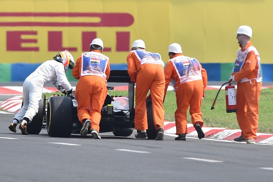 Brautarverðir komnir Fernando Alonso til aðstoðar og hjálpa honum að ýta bílnum heim að bílskúr.