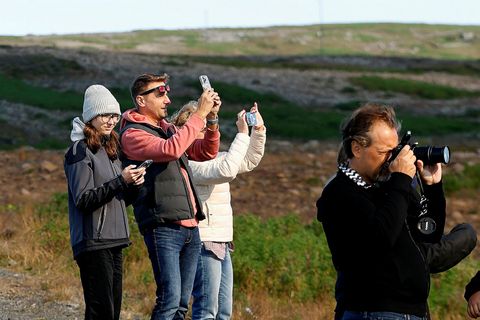 Ferðamenn taka myndir af eldgosi við Sundhnúkagíga.