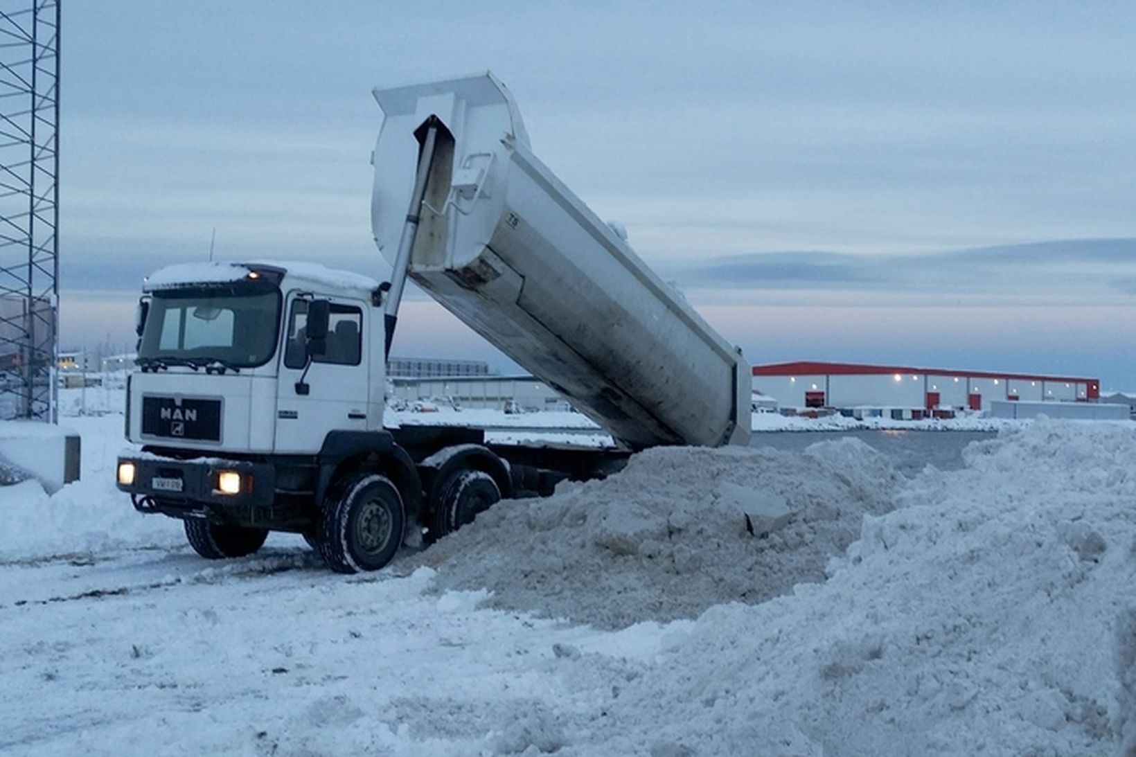 Starfsmenn borgarinnar losa snjó í flæðarmálinu á bak við móttökustöð …