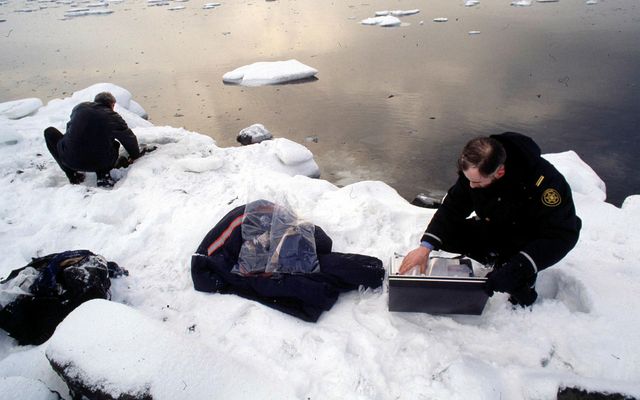 Lögreglumenn rannsaka brunnar peningatöskur í Hvalfirði árið 1995.