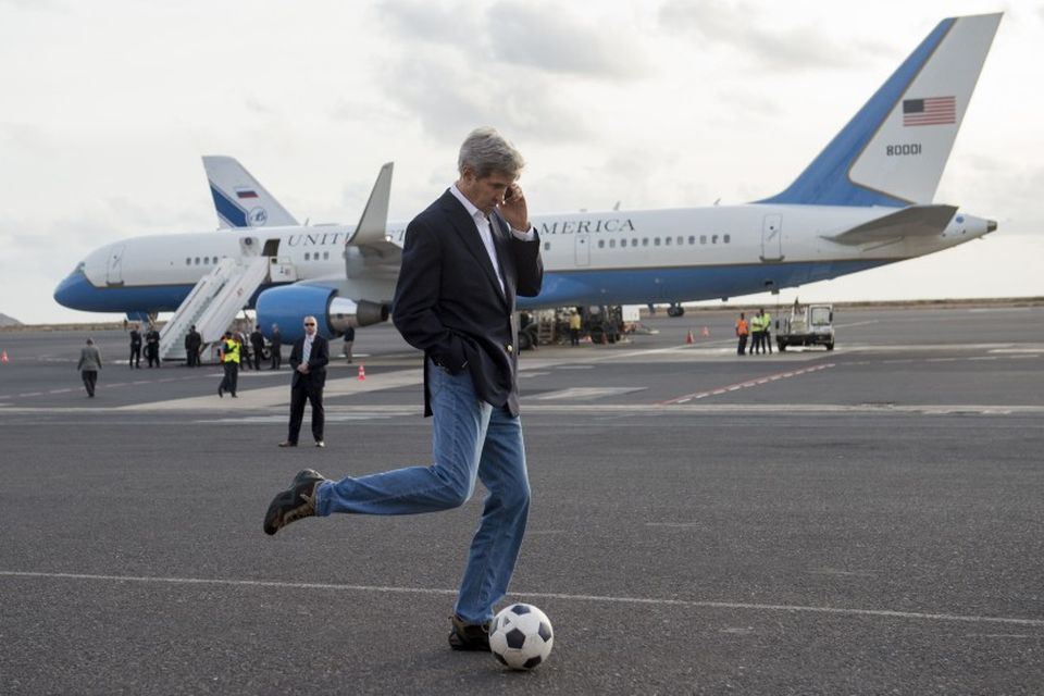 John Kerry, utanríkisráðherra Bandaríkjanna, sparkar í bolta meðan talar í síma og býður eftir að …