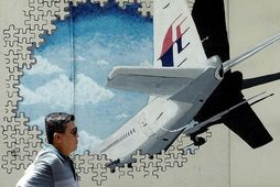 Malasískur maður gengur framhjá veggmynd af MH370-vélinni.