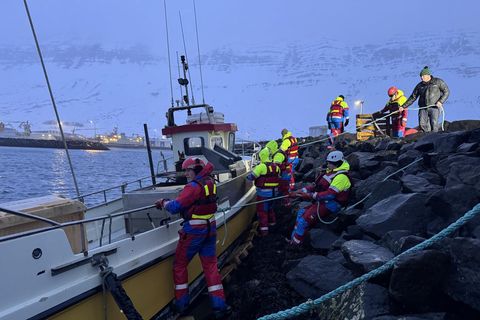 Björgunarsveitarmenn taka á honum stóra sínum á Norðfirði í morgun þar sem bátur slitnaði frá …