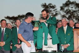 Scottie Scheffler klæðir Rory McIlroy í græna jakkann í gær. Scheffler er efsti kylfingur heimslistans …