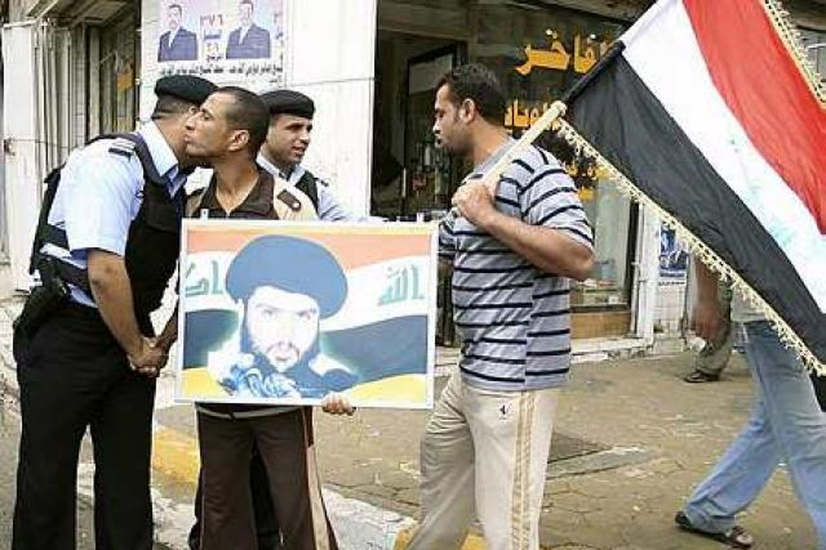 Stuðningsmenn Moqtada al-Sadr bera mynd af honum í mótmælagöngu í …